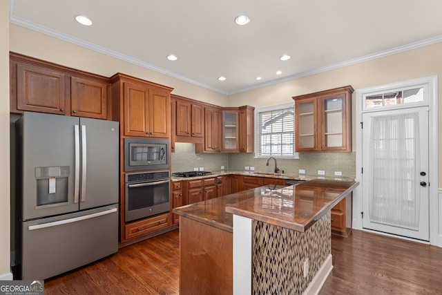 kitchen with tasteful backsplash, appliances with stainless steel finishes, sink, a center island, and dark hardwood / wood-style flooring