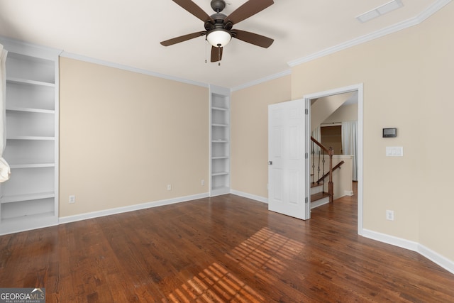 empty room with crown molding, dark hardwood / wood-style flooring, built in shelves, and ceiling fan