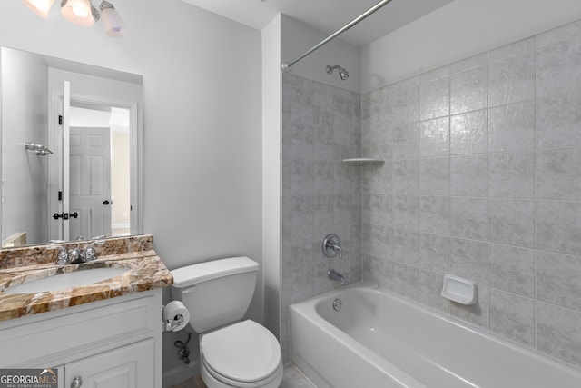 full bathroom with tiled shower / bath, vanity, and toilet