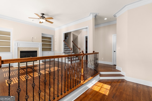 corridor with crown molding, built in features, and dark hardwood / wood-style flooring