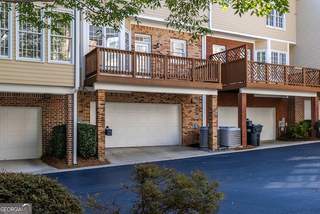 rear view of house featuring central AC unit, a garage, and a balcony