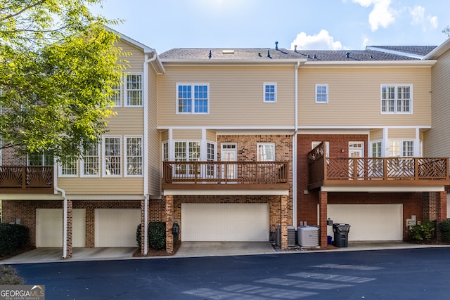 rear view of property featuring central air condition unit, a garage, and a balcony