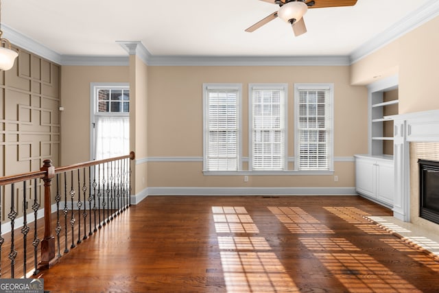 unfurnished living room featuring ornamental molding, built in shelves, dark hardwood / wood-style floors, and ceiling fan