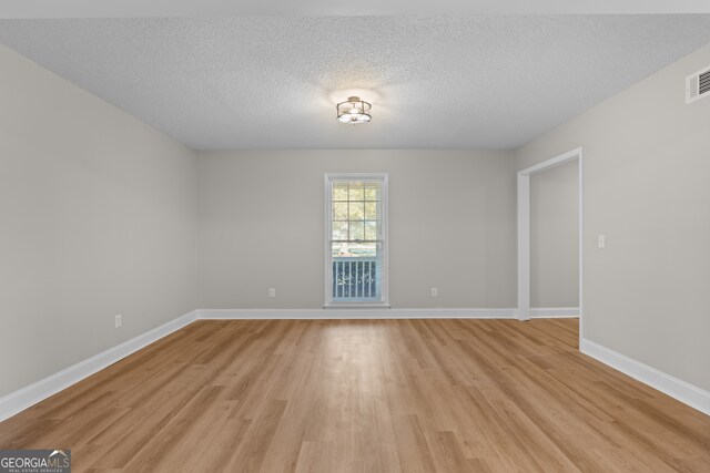 spare room featuring a textured ceiling and light wood-type flooring