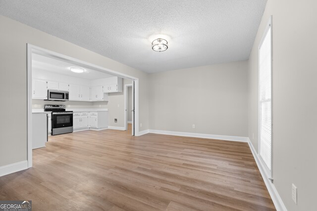 unfurnished living room with a textured ceiling and light wood-type flooring