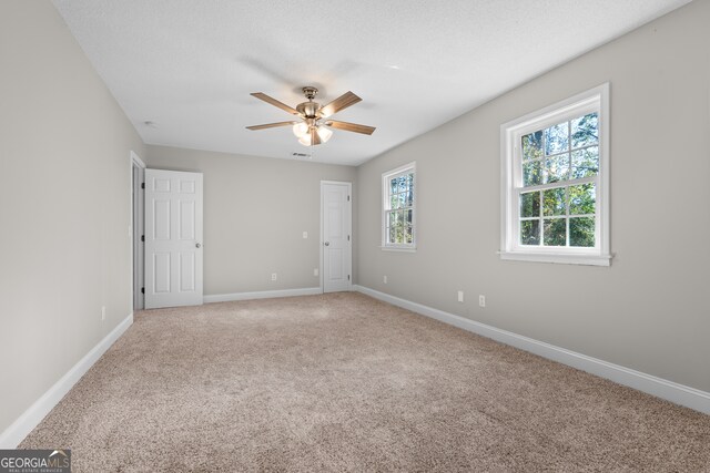 carpeted empty room featuring ceiling fan and a textured ceiling