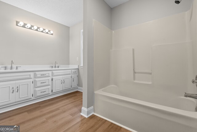 bathroom featuring  shower combination, vanity, hardwood / wood-style floors, and a textured ceiling