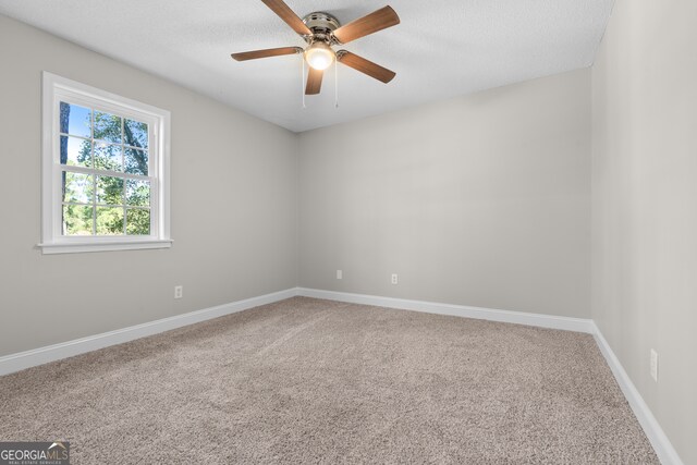 spare room with a textured ceiling, carpet floors, and ceiling fan