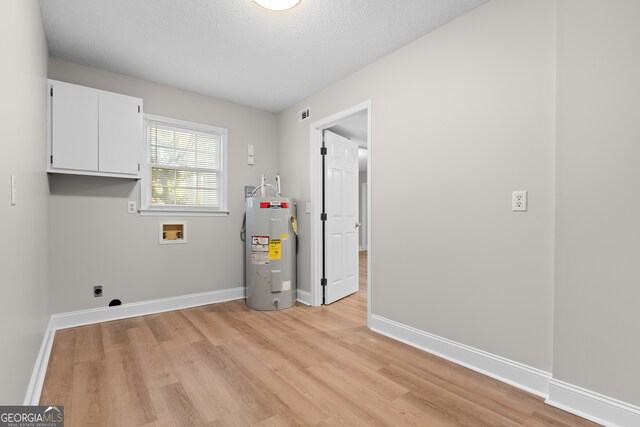 laundry area featuring hookup for a washing machine, electric water heater, hookup for an electric dryer, cabinets, and light hardwood / wood-style floors