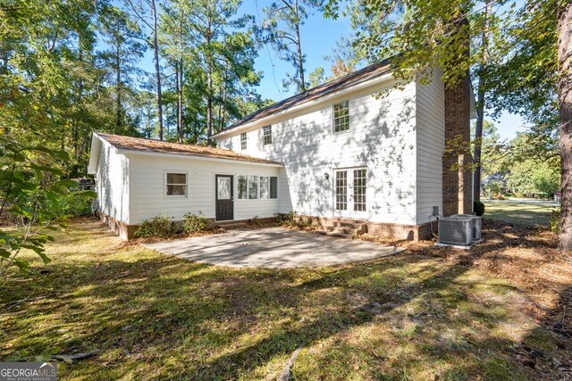 back of house featuring central air condition unit, a patio area, and a lawn