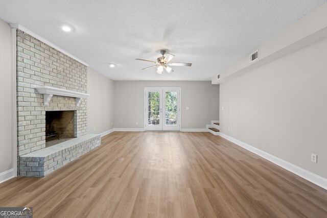 unfurnished living room featuring light hardwood / wood-style floors, a textured ceiling, a fireplace, and ceiling fan