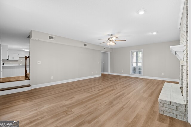 unfurnished living room featuring ceiling fan, light wood-type flooring, and a fireplace