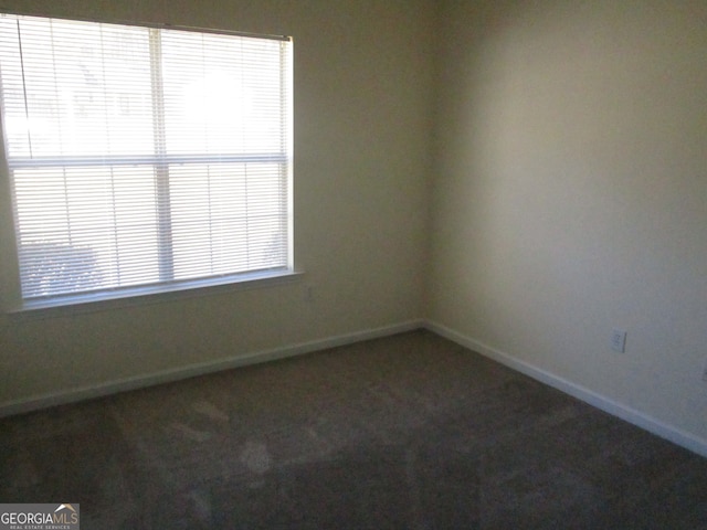 spare room with dark colored carpet