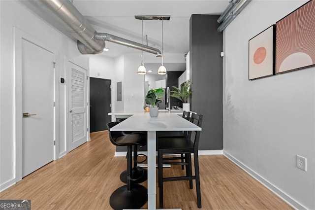 dining room featuring electric panel and light hardwood / wood-style flooring