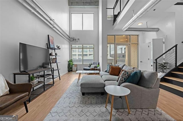 living room with a towering ceiling, hardwood / wood-style floors, and a wealth of natural light