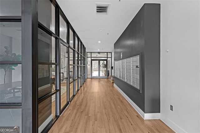 hallway featuring floor to ceiling windows, mail boxes, and light wood-type flooring