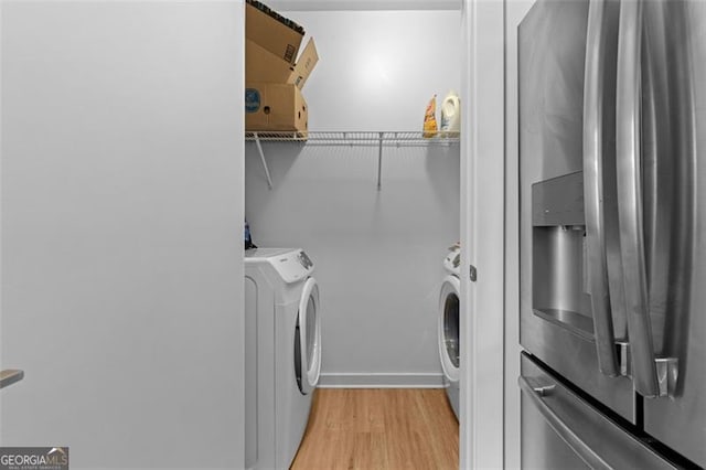 washroom with washer and clothes dryer and light wood-type flooring