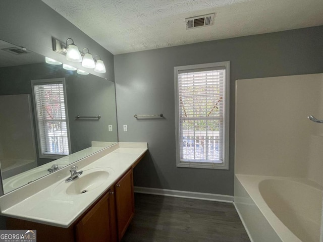 bathroom with vanity, a tub, a textured ceiling, and hardwood / wood-style floors