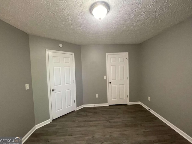 unfurnished room featuring a textured ceiling and dark hardwood / wood-style flooring