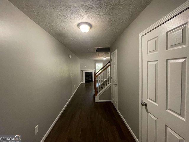 corridor with dark hardwood / wood-style floors and a textured ceiling