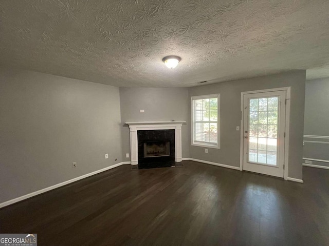 unfurnished living room with dark wood-type flooring and a textured ceiling