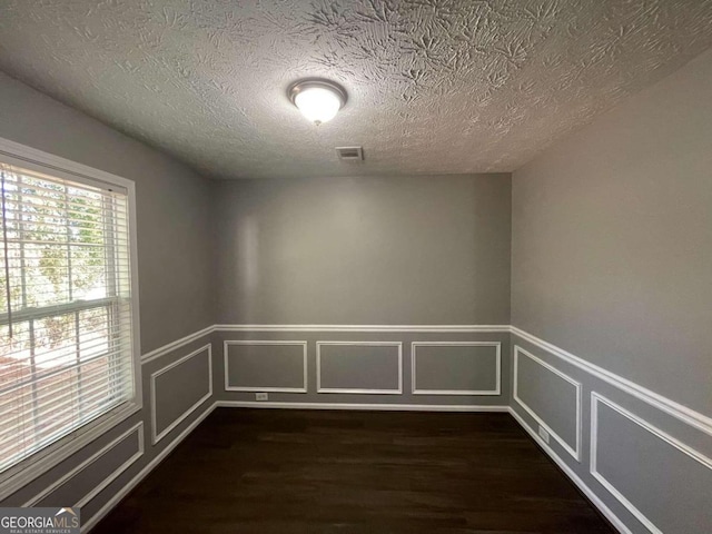 unfurnished room featuring a textured ceiling and dark hardwood / wood-style floors