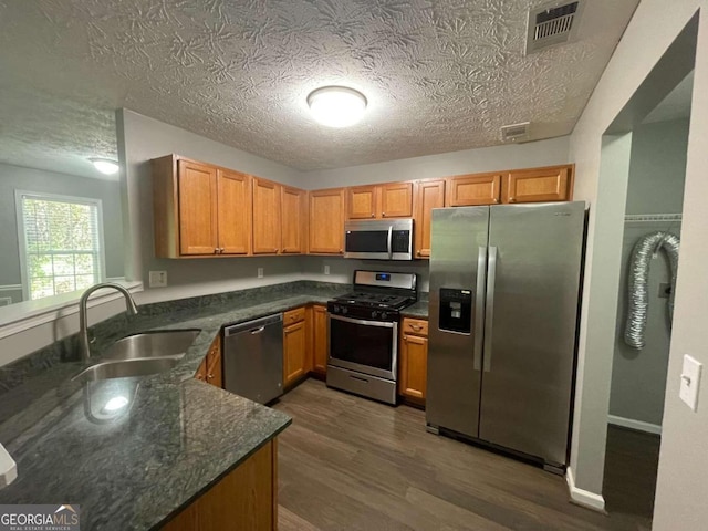 kitchen featuring dark hardwood / wood-style floors, stainless steel appliances, sink, and a textured ceiling