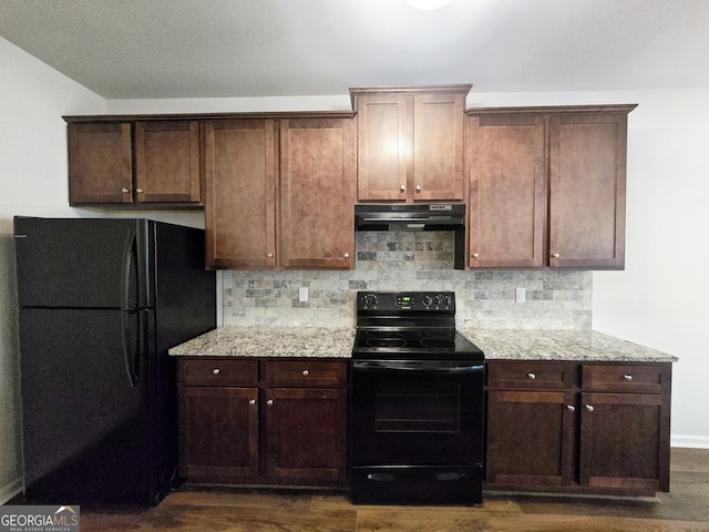 kitchen featuring black appliances, light stone counters, dark hardwood / wood-style floors, and backsplash