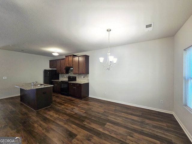 kitchen featuring decorative backsplash, dark hardwood / wood-style floors, an island with sink, black appliances, and decorative light fixtures