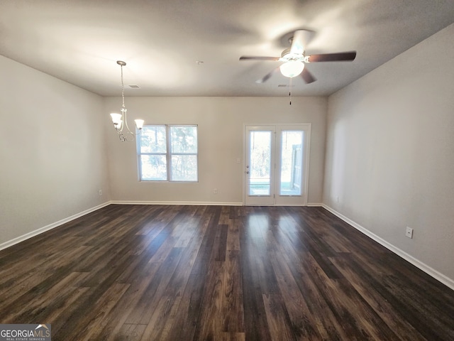 empty room with dark wood-type flooring and ceiling fan with notable chandelier