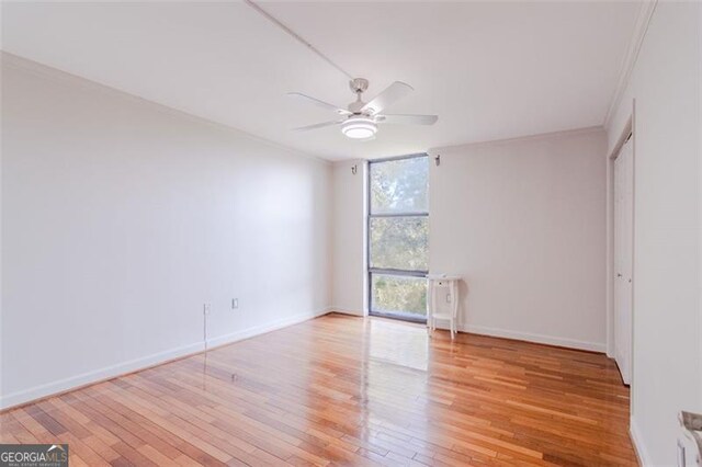 spare room featuring light hardwood / wood-style flooring, ceiling fan, floor to ceiling windows, and crown molding