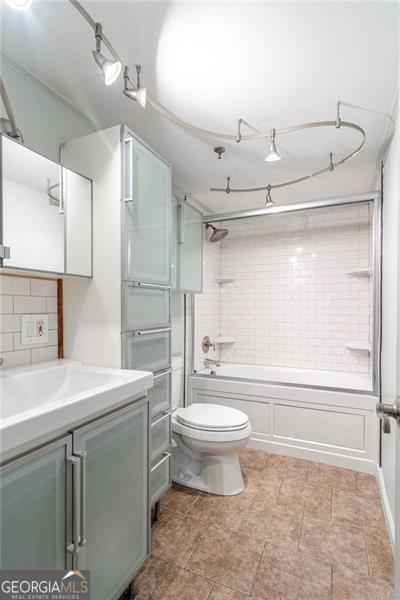 full bathroom with vanity, decorative backsplash, tiled shower / bath combo, and toilet