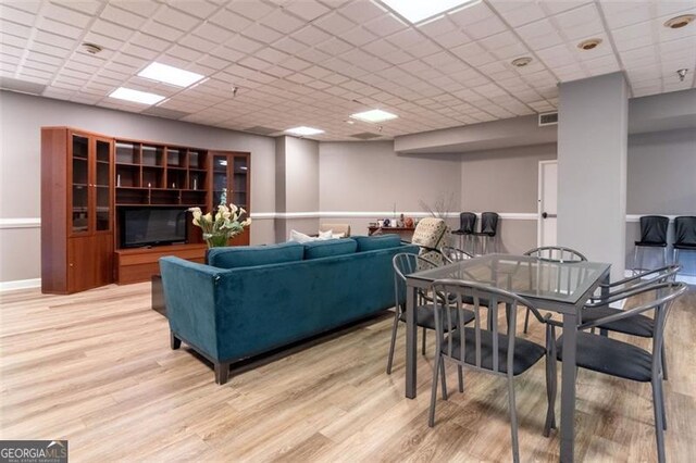 living room featuring light hardwood / wood-style floors and a drop ceiling