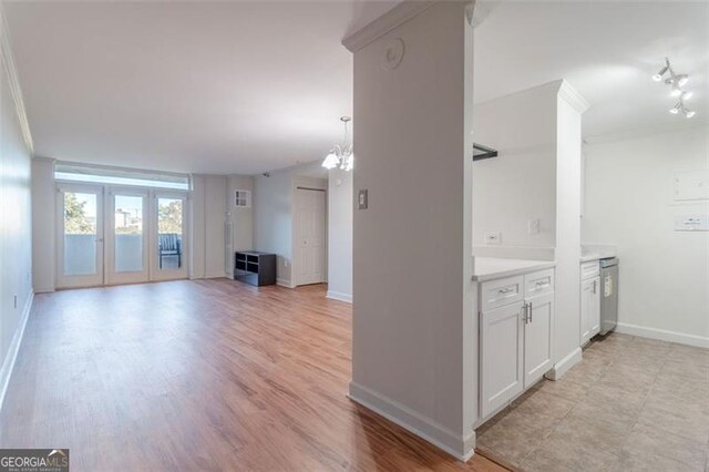 unfurnished living room with light hardwood / wood-style flooring, french doors, a chandelier, and crown molding