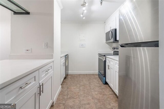 kitchen with appliances with stainless steel finishes, crown molding, and white cabinetry