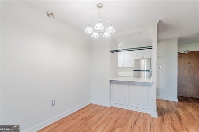 unfurnished dining area with crown molding, light hardwood / wood-style flooring, and a notable chandelier