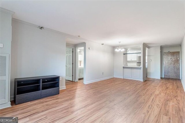 unfurnished living room with ornamental molding, a chandelier, and light wood-type flooring