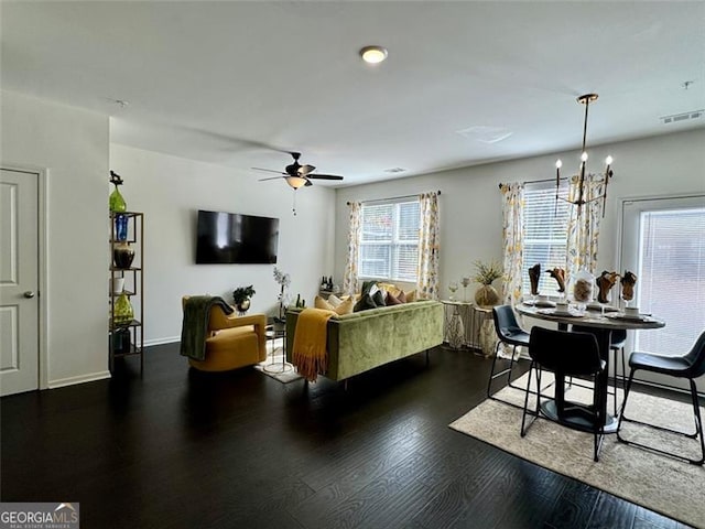 living room featuring dark wood-type flooring and ceiling fan with notable chandelier