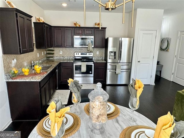 kitchen featuring dark brown cabinetry, decorative backsplash, light stone counters, and stainless steel appliances