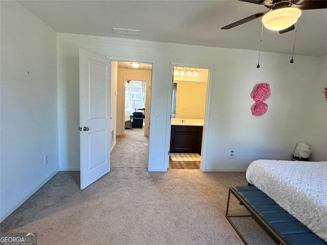 carpeted bedroom with ensuite bath, sink, and ceiling fan