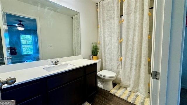 bathroom with hardwood / wood-style floors, ceiling fan, toilet, vanity, and a shower with curtain