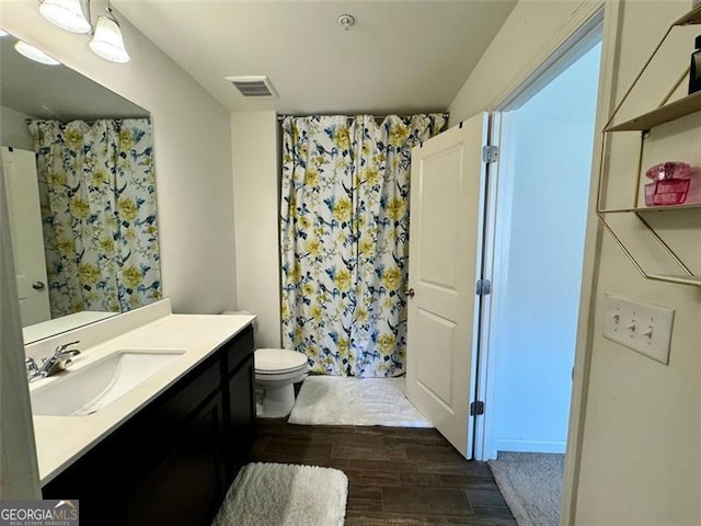 bathroom featuring toilet, hardwood / wood-style floors, curtained shower, and vanity