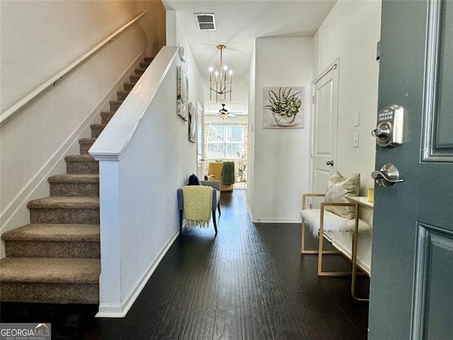 foyer entrance with dark wood-type flooring and a notable chandelier