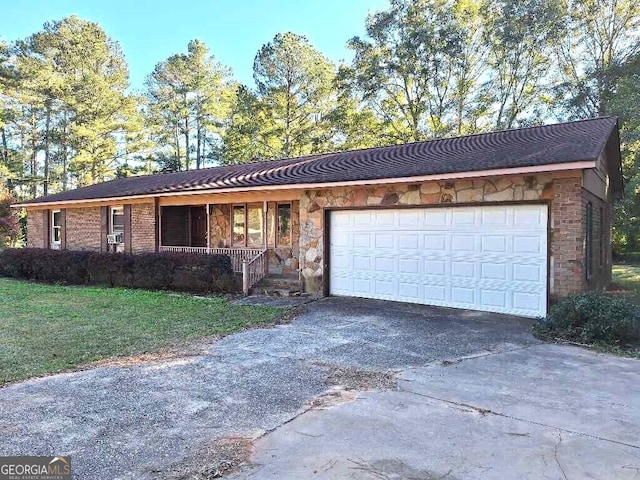 ranch-style home with covered porch, a front yard, and a garage