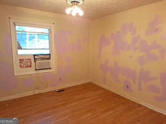 spare room with cooling unit, a textured ceiling, hardwood / wood-style flooring, and ceiling fan