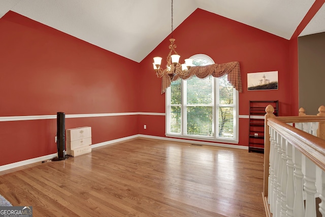 interior space featuring high vaulted ceiling, hardwood / wood-style flooring, and an inviting chandelier