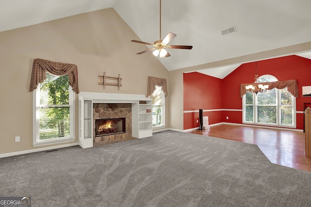 unfurnished living room with carpet, high vaulted ceiling, ceiling fan with notable chandelier, and a fireplace