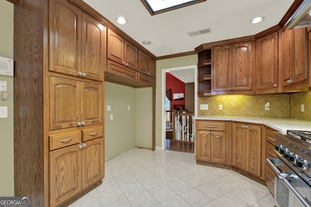 kitchen with decorative backsplash, light tile patterned floors, high end stainless steel range oven, ornamental molding, and a skylight