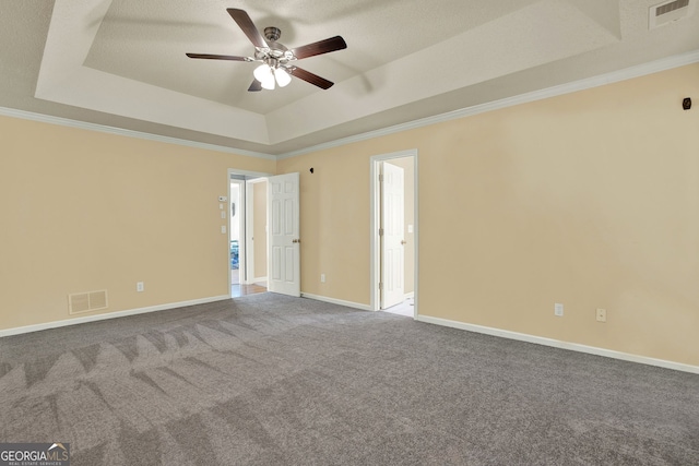 unfurnished room with ornamental molding, a tray ceiling, and carpet flooring