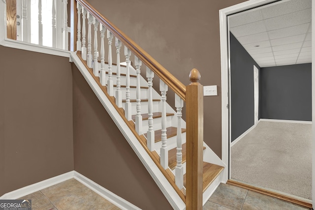 stairs featuring a drop ceiling and tile patterned floors